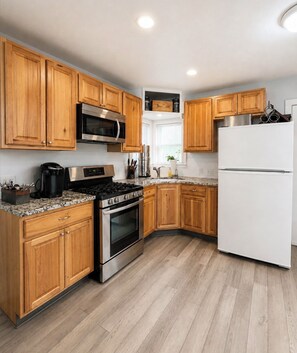 A kitchen with wooden cabinets, stainless steel appliances, a white refrigerator, and a granite countertop. - Near Airport, Golf & Medical Center - California King Bed (San Antonio)