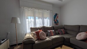 Un salon avec un canapé, des coussins, une lampe et un tableau au mur.