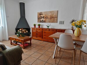Ein Wohnzimmer mit Kamin, Holzmöbeln, einem Esstisch und einem Gemälde an der Wand.