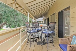 Eine Terrasse im Freien mit Tisch und Stühlen, einem Rattansofa und Blick auf einen Baum.
