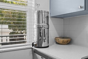A kitchen with a stainless steel water dispenser, a bowl, and a window with blinds. - Chic Clarksville Condo w/ Covered Patio & Gated Keypad Entry - Near Downtown (Austin)