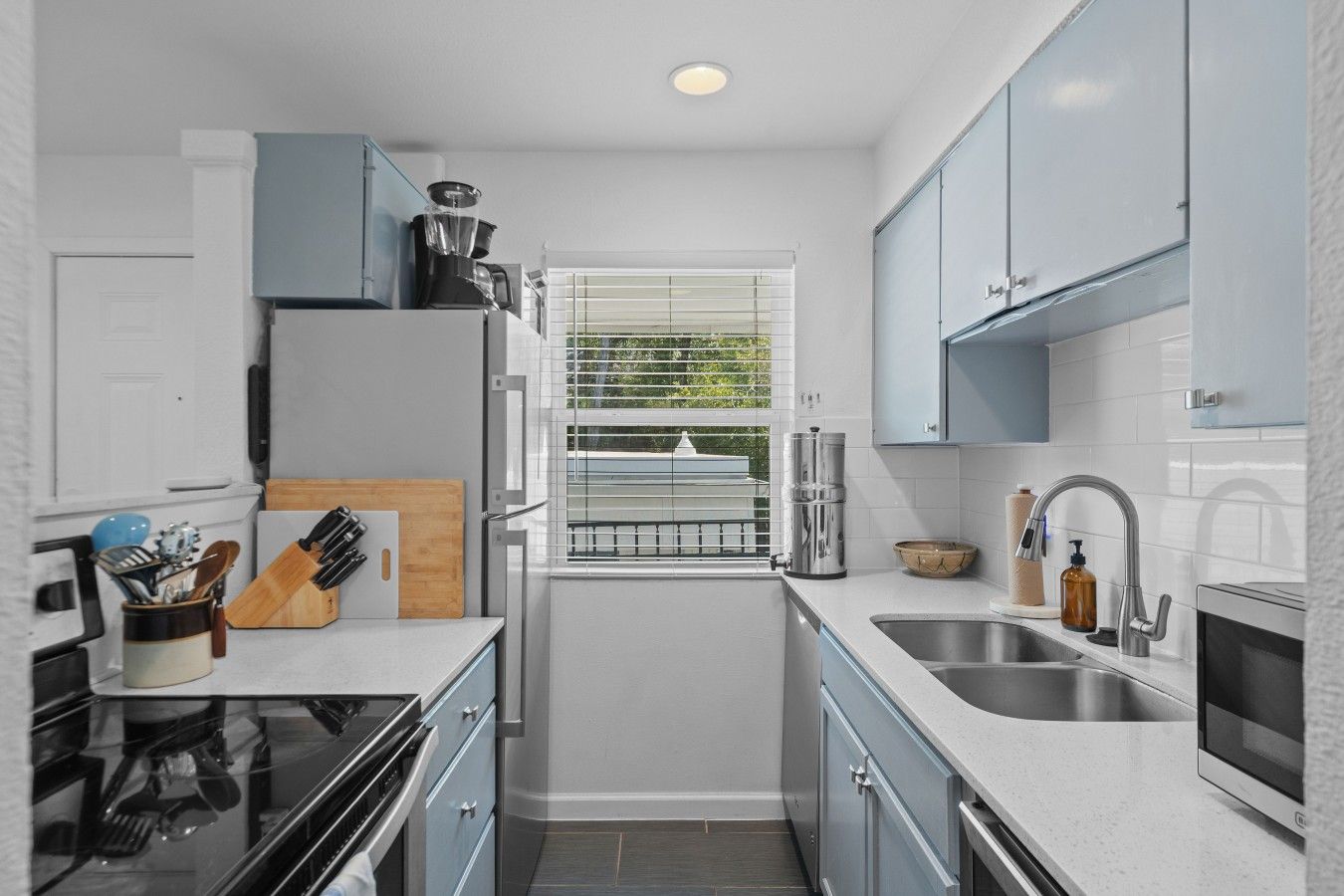 A compact kitchen with a built-in oven, a sink, and a window with a view of the outdoors.