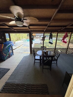 An indoor patio area with a table and chairs, a ceiling fan, and a view of a backyard with a pool. - Spacious 4-bedroom house in Graham: Hot tub, Pool, Dog-friendly w/fenced yard (Graham)