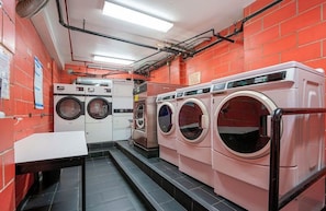 A laundry facility with multiple washing machines, a table, and a tiled floor.
