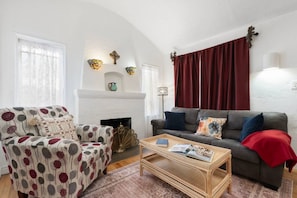 Ein Wohnzimmer mit Kamin, zwei Sofas, einem Couchtisch und dekorativen Wandleuchten.