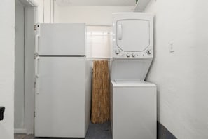 Ein kleiner Hauswirtschaftsraum mit einem weißen Kühlschrank, einer Waschmaschine und einem Trockner.