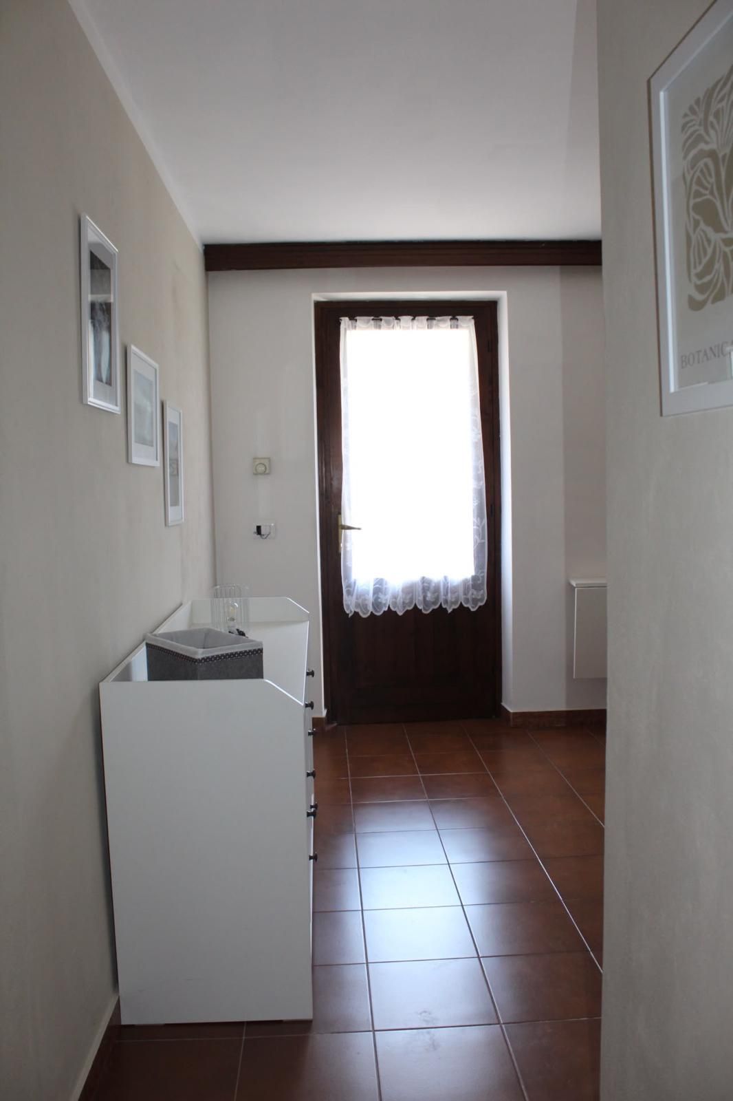 A room with a white cabinet, a window with a curtain, and a tiled floor.