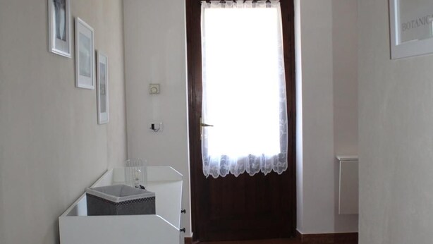 A room with a white cabinet, a window with a curtain, and a tiled floor.