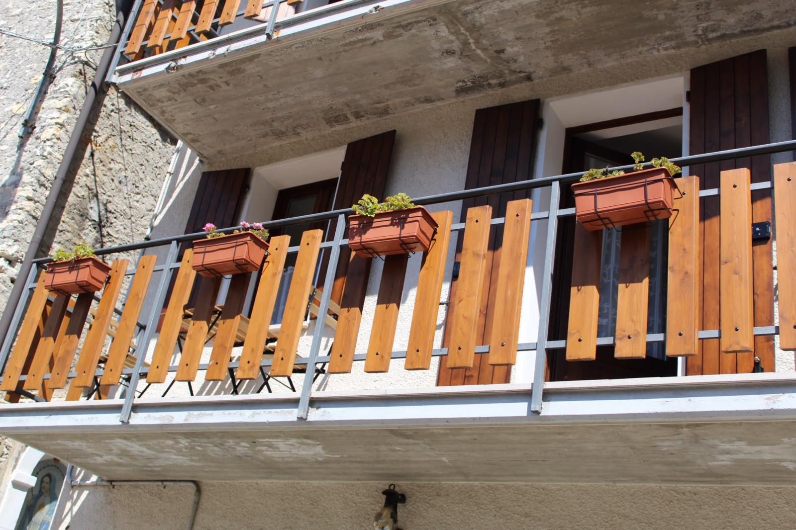 A balcony with wooden railings and multiple flower boxes.