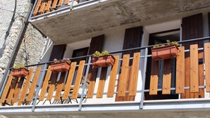 A balcony with wooden railings and multiple flower boxes.
