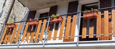A balcony with wooden railings and multiple flower boxes.