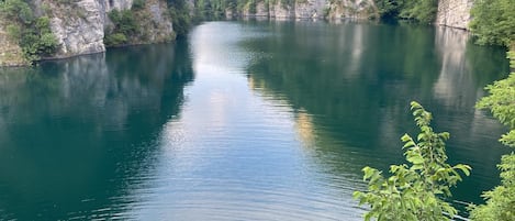 A calm river surrounded by cliffs and greenery.