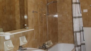 Et badeværelse med bruser, to håndvaske, toilet og spejl.