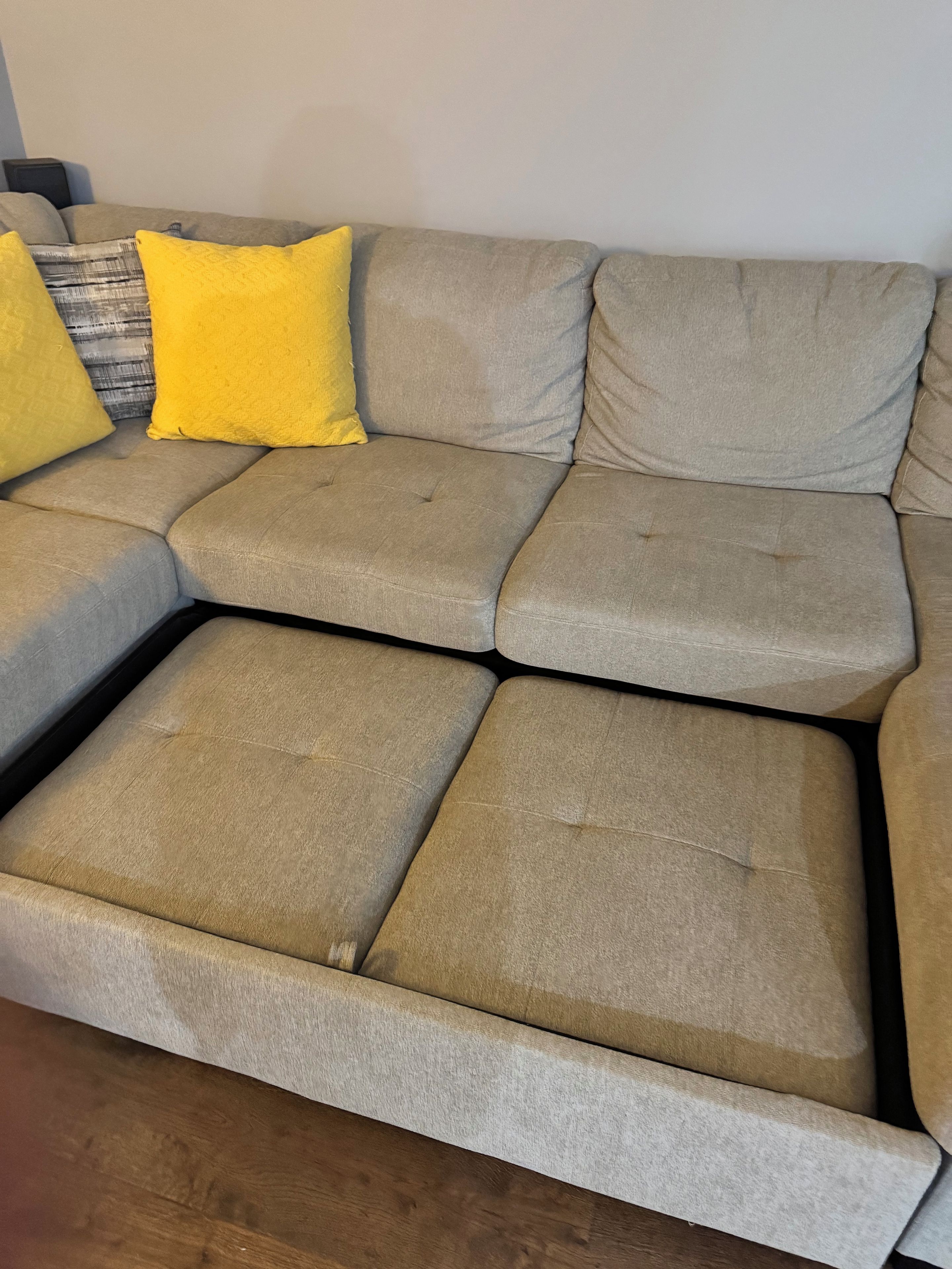 A sectional sofa with multiple cushions and a wooden floor.