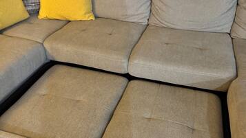 A sectional sofa with multiple cushions and a wooden floor.