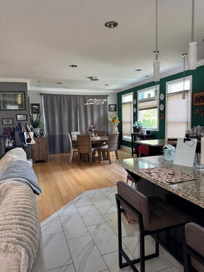 A modern kitchen with a dining area, wooden flooring, and a view of the outdoors.