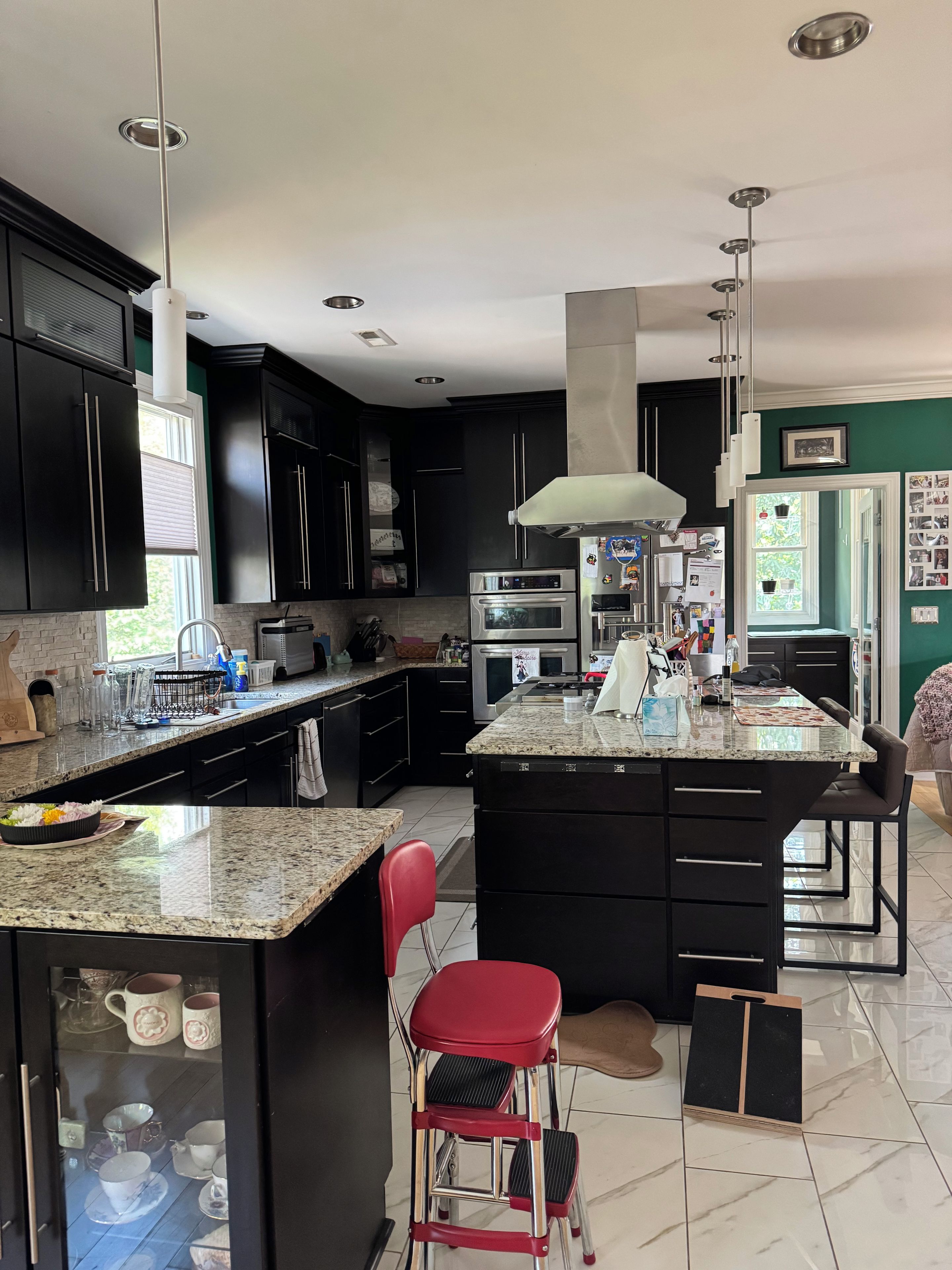 A modern kitchen with dark cabinetry, granite countertops, stainless steel appliances, and a central island with seating.
