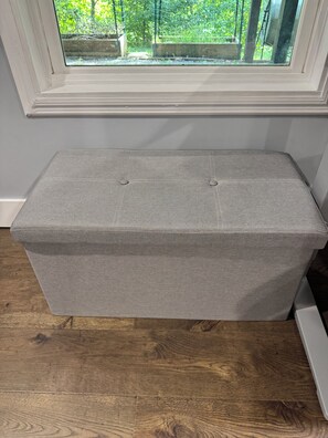 A grey upholstered bench with a window view.