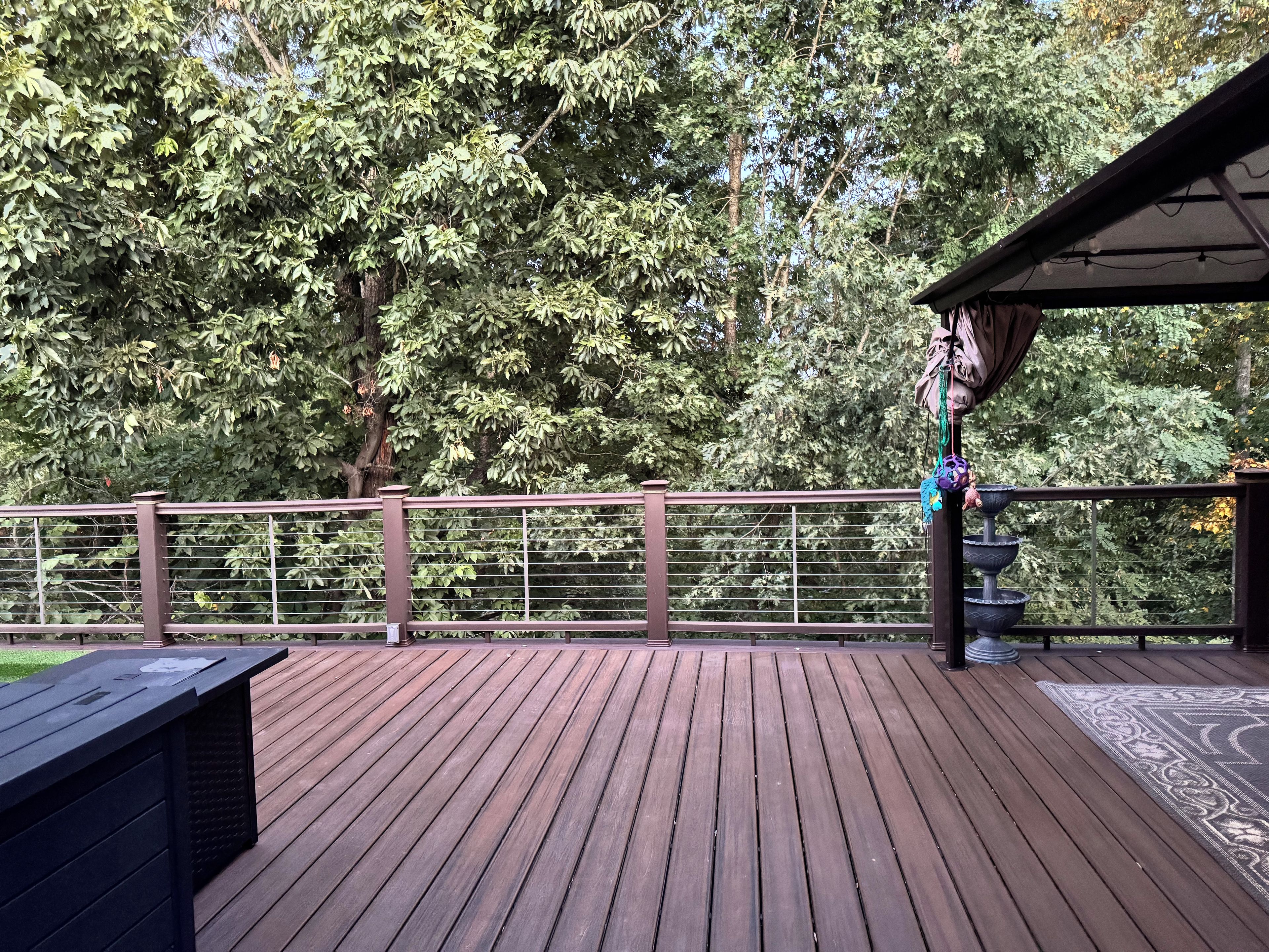 A wooden deck with a railing, a pergola, and a tiered water feature.