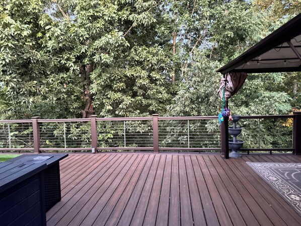 A wooden deck with a railing, a pergola, and a tiered water feature.