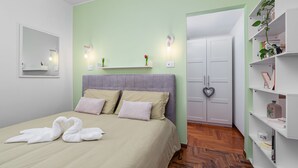 Una camera da letto con un letto, uno specchio, un armadio e uno scaffale con libri e una pianta.