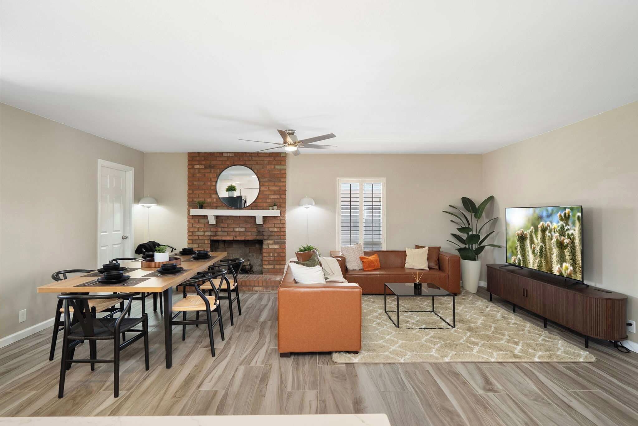 A spacious living area with a fireplace, a dining table with chairs, a sofa, a coffee table, and a television.