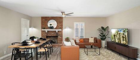 A spacious living area with a fireplace, a dining table with chairs, a sofa, a coffee table, and a television.