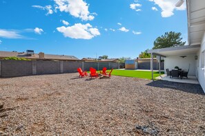 A backyard with a gravel patio, a green lawn, and a covered outdoor seating area with chairs. - Glendale Retreat Spacious Yard & RV Parking (Glendale)