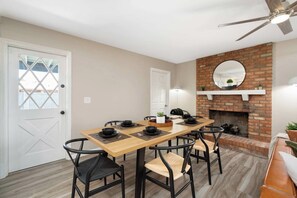 A dining area with a wooden table, black chairs, and a brick fireplace. - Glendale Retreat Spacious Yard & RV Parking (Glendale)