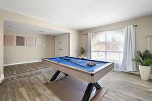 A pool table in a room with a large window, a potted plant, and artwork on the wall. - Glendale Retreat Spacious Yard & RV Parking (Glendale)