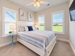 A bedroom with a bed, two bedside tables, a ceiling fan, and large windows with blinds. - Barefoot Resort Getaway | Golf, Pool & Beach (North Myrtle Beach)