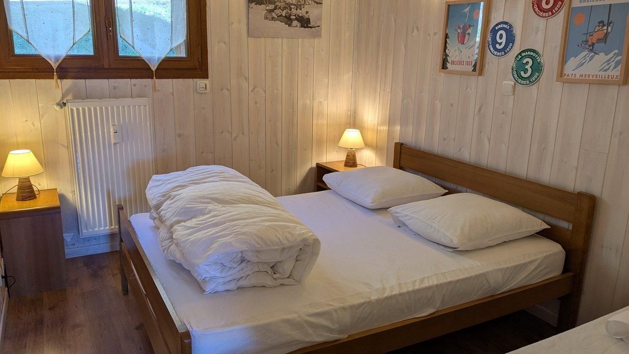 A wooden-framed bed with white bedding, two bedside lamps, and a radiator.