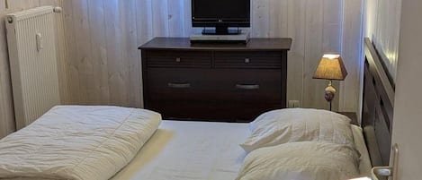 A bedroom with a bed, a dresser, a television, and wall-mounted lights.
