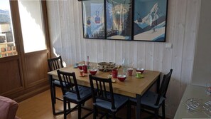 A dining area with a wooden table and chairs, a painting above, and a window with a view. - 100m from ski lifts, 2nd floor, balcony, tv, ski locker, 55m², Orcières Merlette 1850 (Orcières)