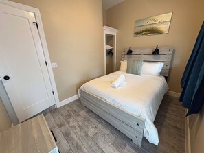 A bedroom with a bed, a painting, a closet, and a door.
