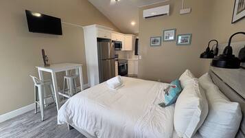 Habitación de hotel con cama, escritorio, silla, ventilador de techo y televisor de pantalla plana.