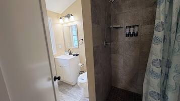 Une salle de bain équipée d’une douche, de toilettes, d’un lavabo et d’un miroir.