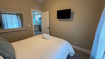 Une chambre d’hôtel avec un lit, un téléviseur fixé au mur et une porte donnant sur une salle de bain.