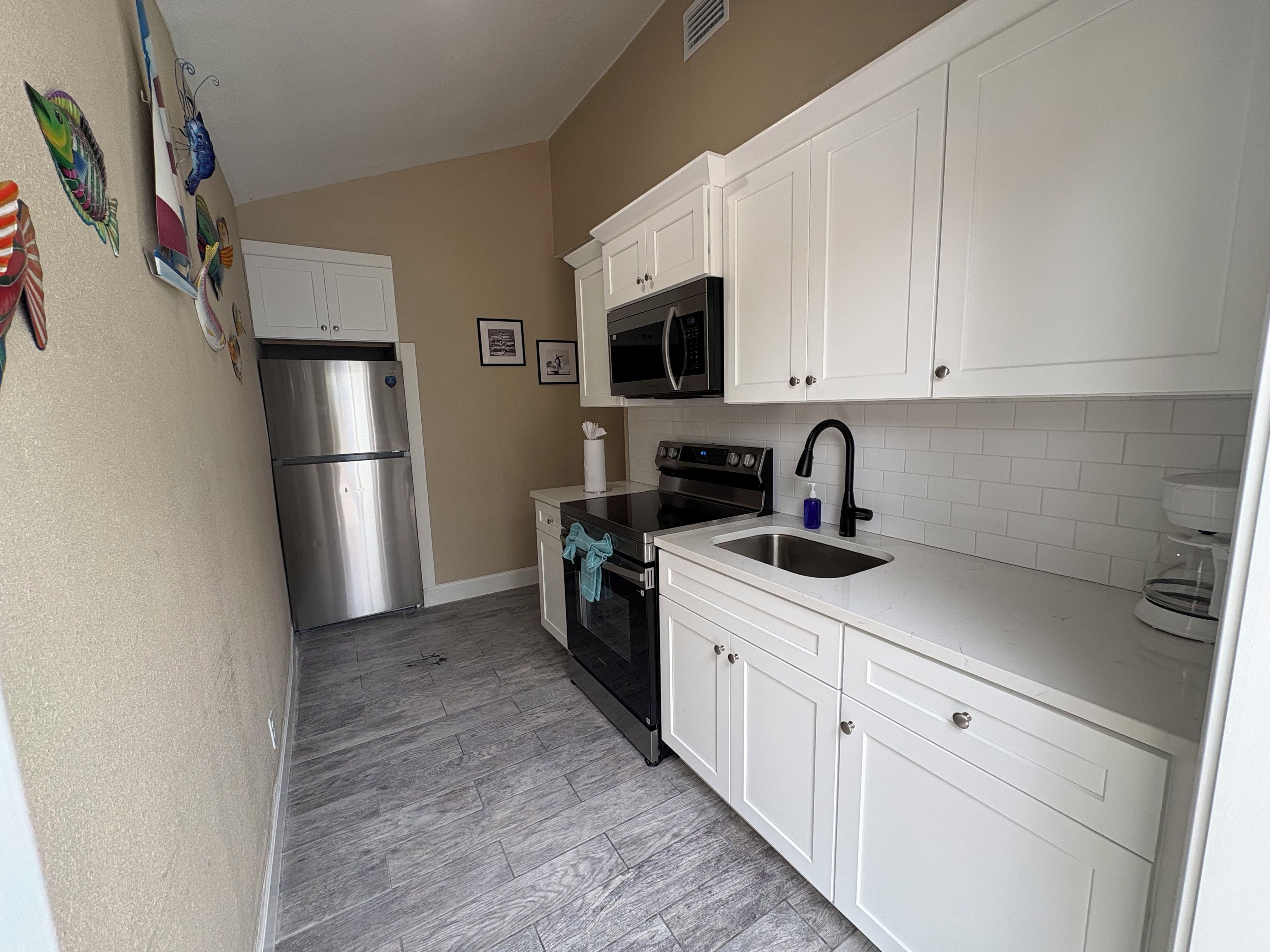 A kitchen with white cabinets, stainless steel appliances, and a tiled backsplash.