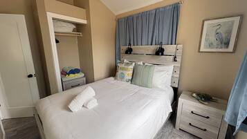 Une chambre à coucher avec un lit, des tables de chevet, une armoire et un tableau encadré au mur.