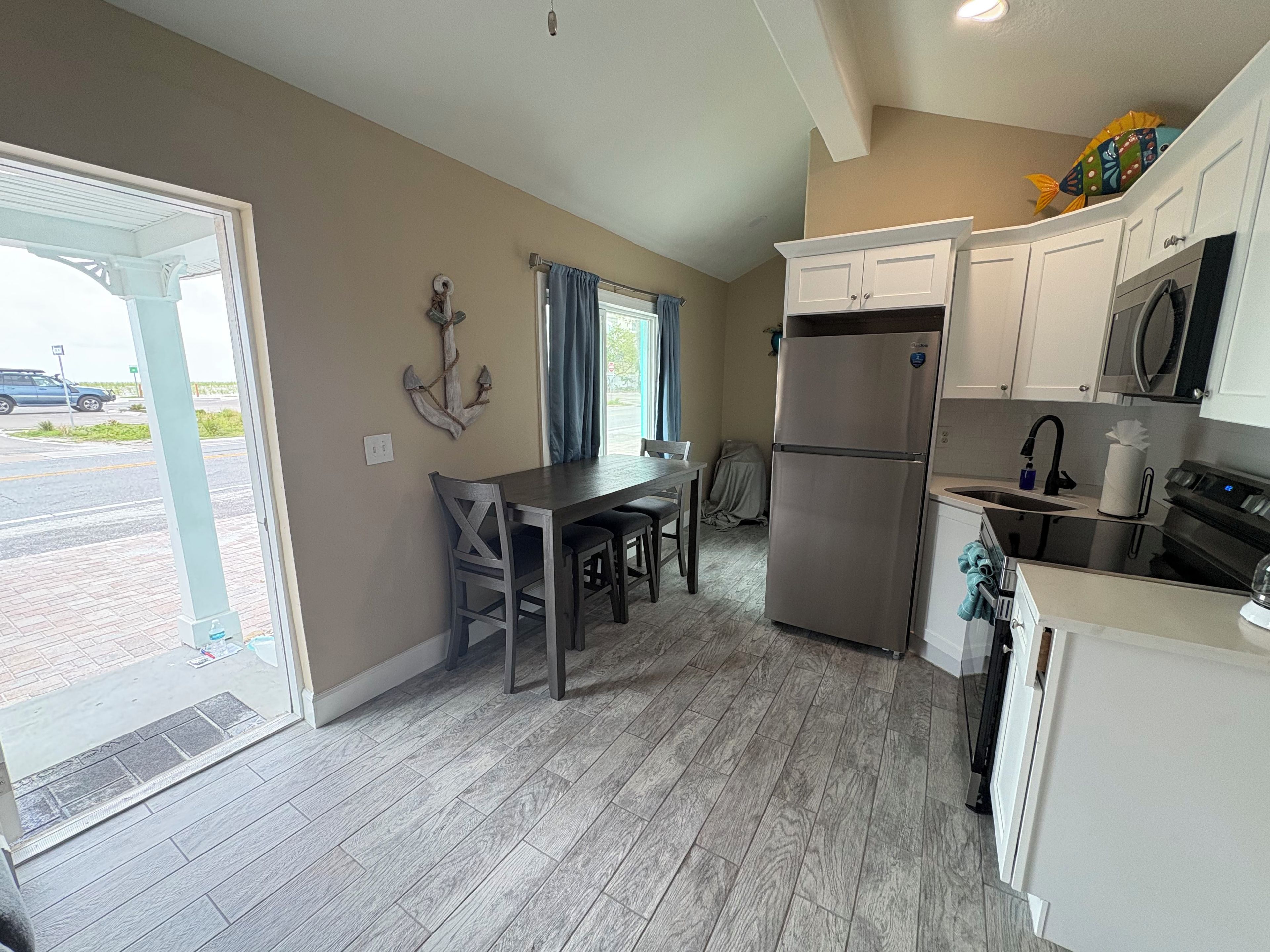 A modern kitchen with a dining area, a refrigerator, and a view of the street.
