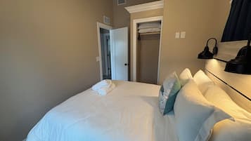Une chambre d’hôtel avec un lit bien fait, un dressing et une lampe de chevet.