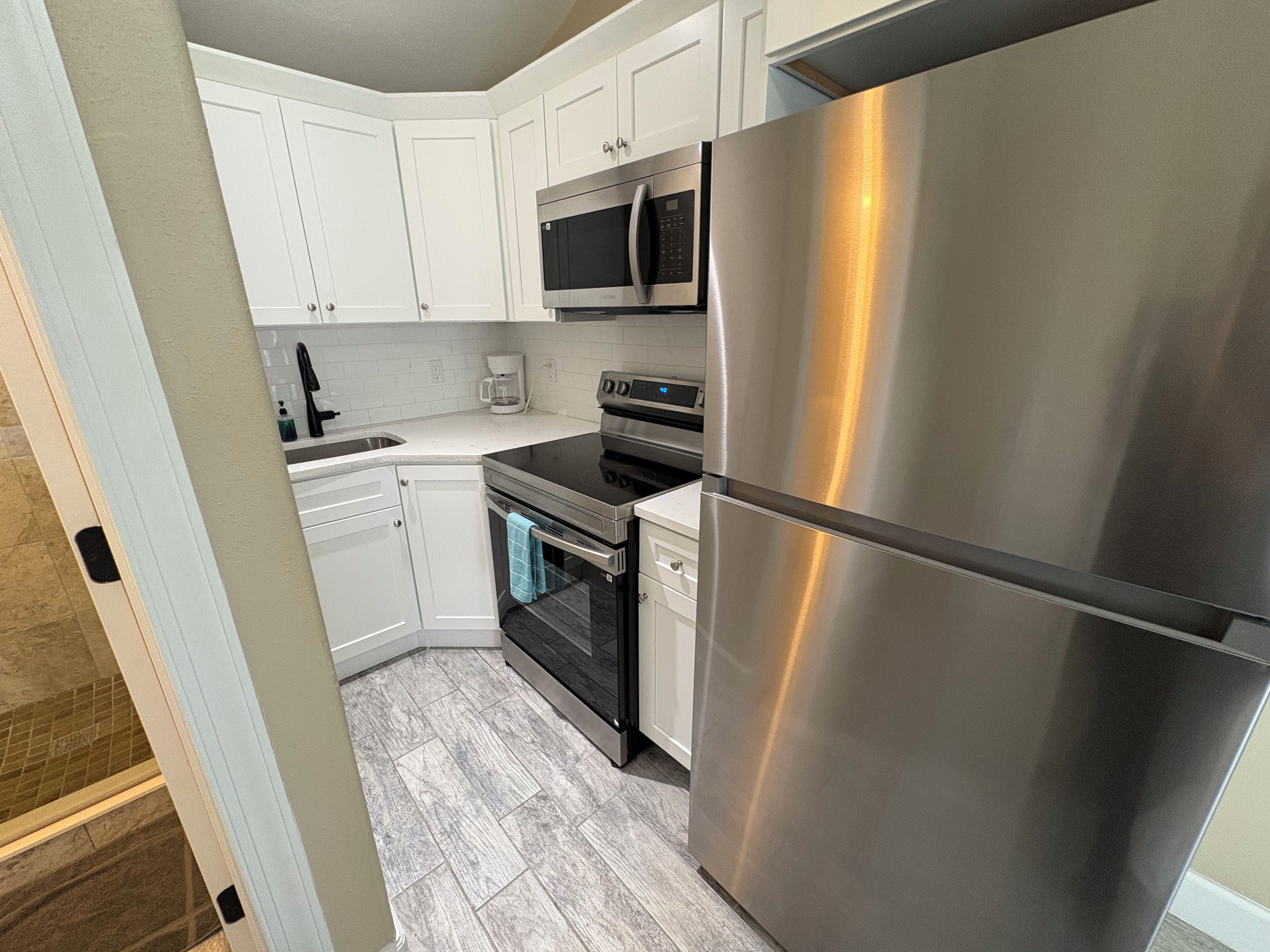 A modern kitchen with stainless steel appliances, white cabinetry, and a tiled backsplash.