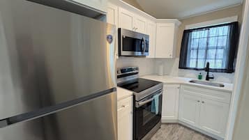 A modern kitchen with stainless steel appliances, white cabinetry, and a window with a view.