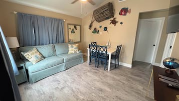 Un salon comprenant un canapé, une table à manger, des chaises, un ventilateur de plafond et des éléments de décoration murale.