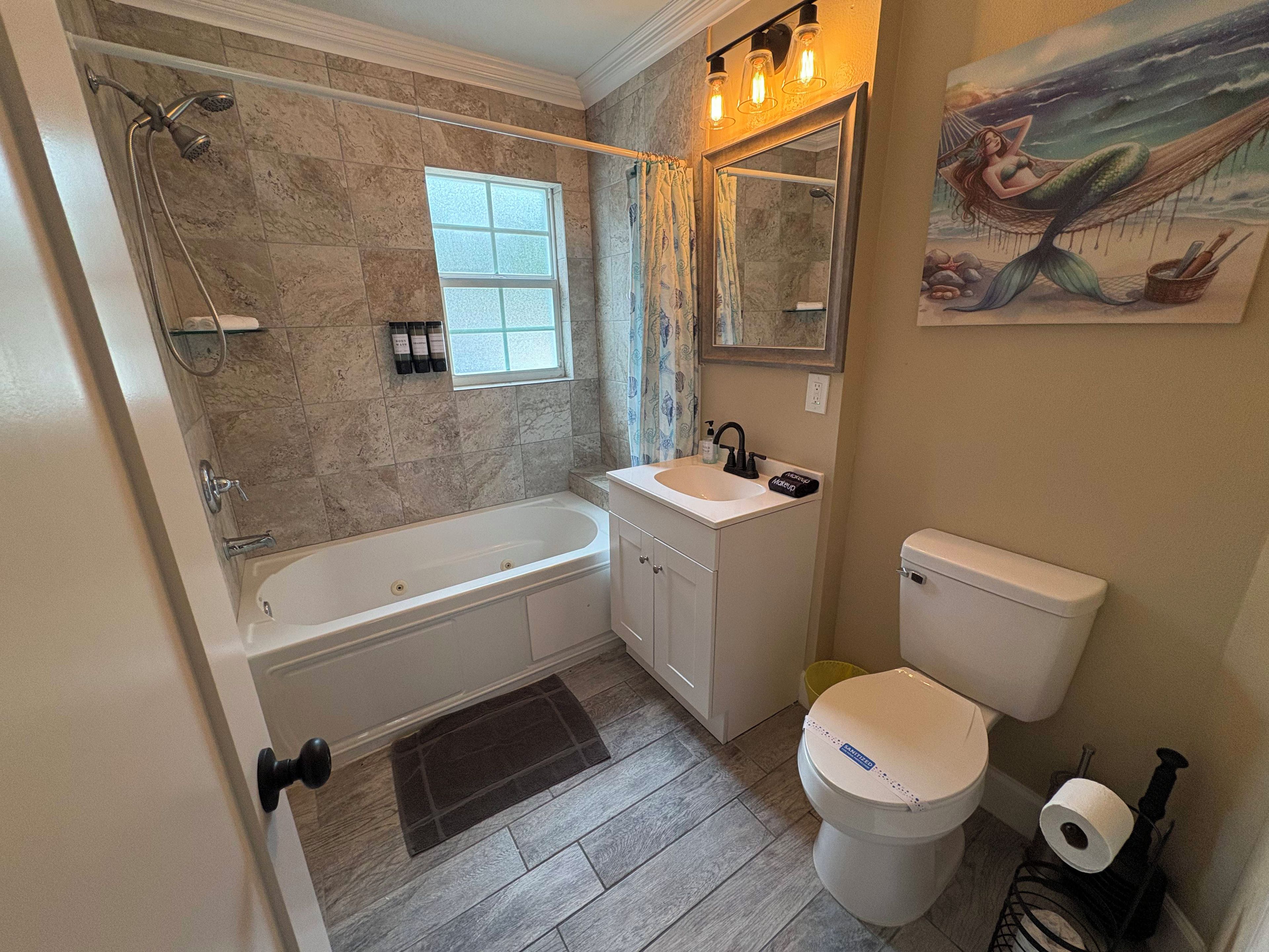 Een badkamer met een bad, wastafel, toilet en douche.