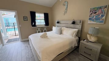 A bedroom with a bed, bedside tables, a window with curtains, a ceiling fan, and a painting on the wall.