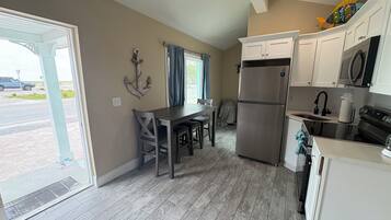 A modern kitchen with a dining area, a refrigerator, and a view of the street.
