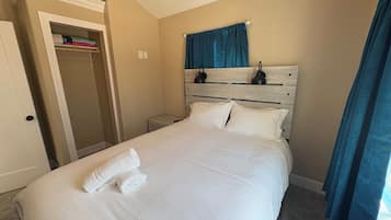 Une chambre d’hôtel avec un lit, une table de chevet, une armoire et une fenêtre avec des rideaux.