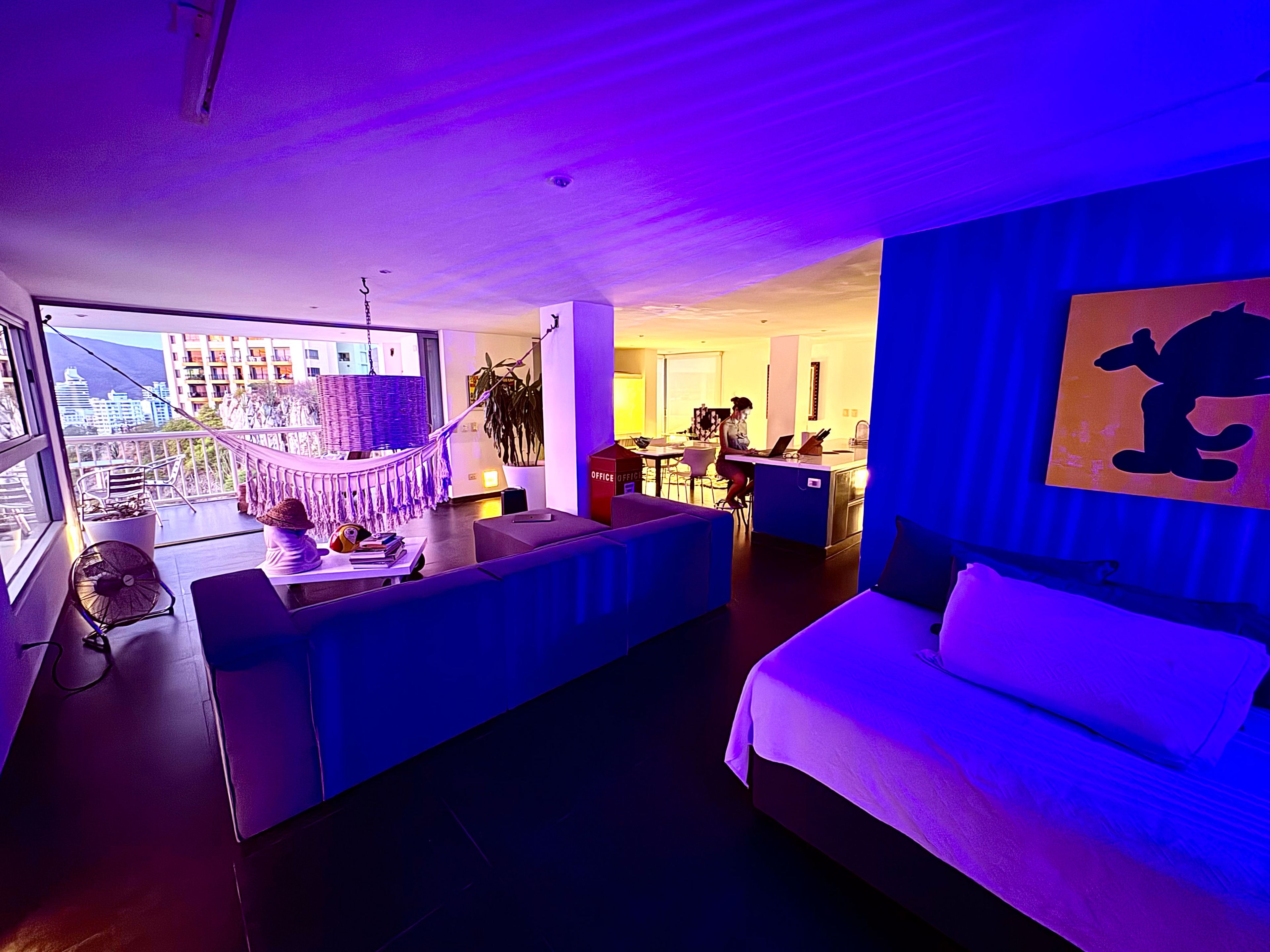 A modern hotel room with a balcony, a desk, and a bed.